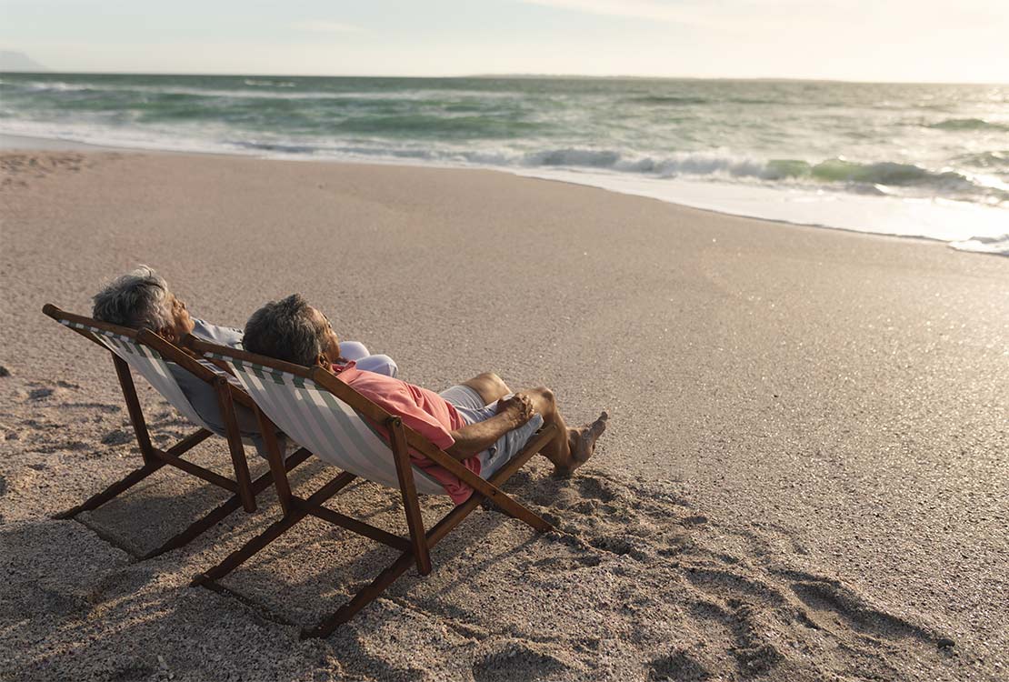 couple lounging in chairs on the beach retire well