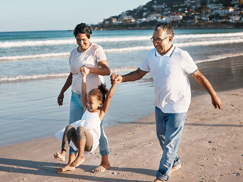 grandparents walking with their granddaughter on the beach safe income strategy for retirement